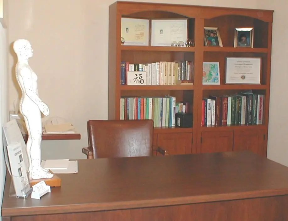 Acupuncture point model and framed credentials at the Acuherb Clinic consulting desk