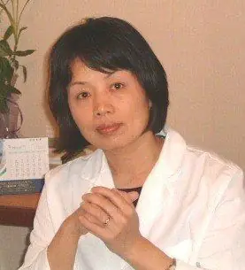 Dr. Helen H. Liu, L.Ac., O.M.D., seated at her desk in a white coat